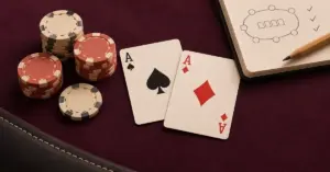 Pocket aces beside neatly stacked poker chips and a strategy notebook on aubergine felt, illustrating thoughtful play for beginners.
