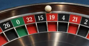 A close-up of an ivory ball on a roulette wheel above red and black numbered pockets and the green zero.