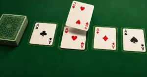 A two of hearts hovers above the ace of hearts among four solitaire foundations on green felt, beside a face-down stock pile.