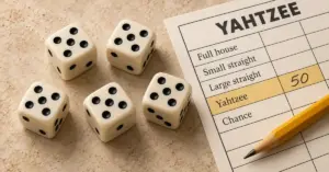 Five dice showing fives beside a Yahtzee scorecard with 50 points recorded and a yellow pencil.